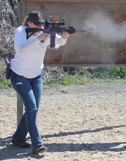 A woman shooting a gun wearing gun