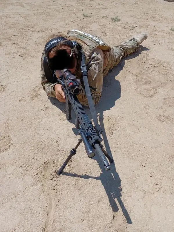 Young male sniper in camouflage with gun in the desert